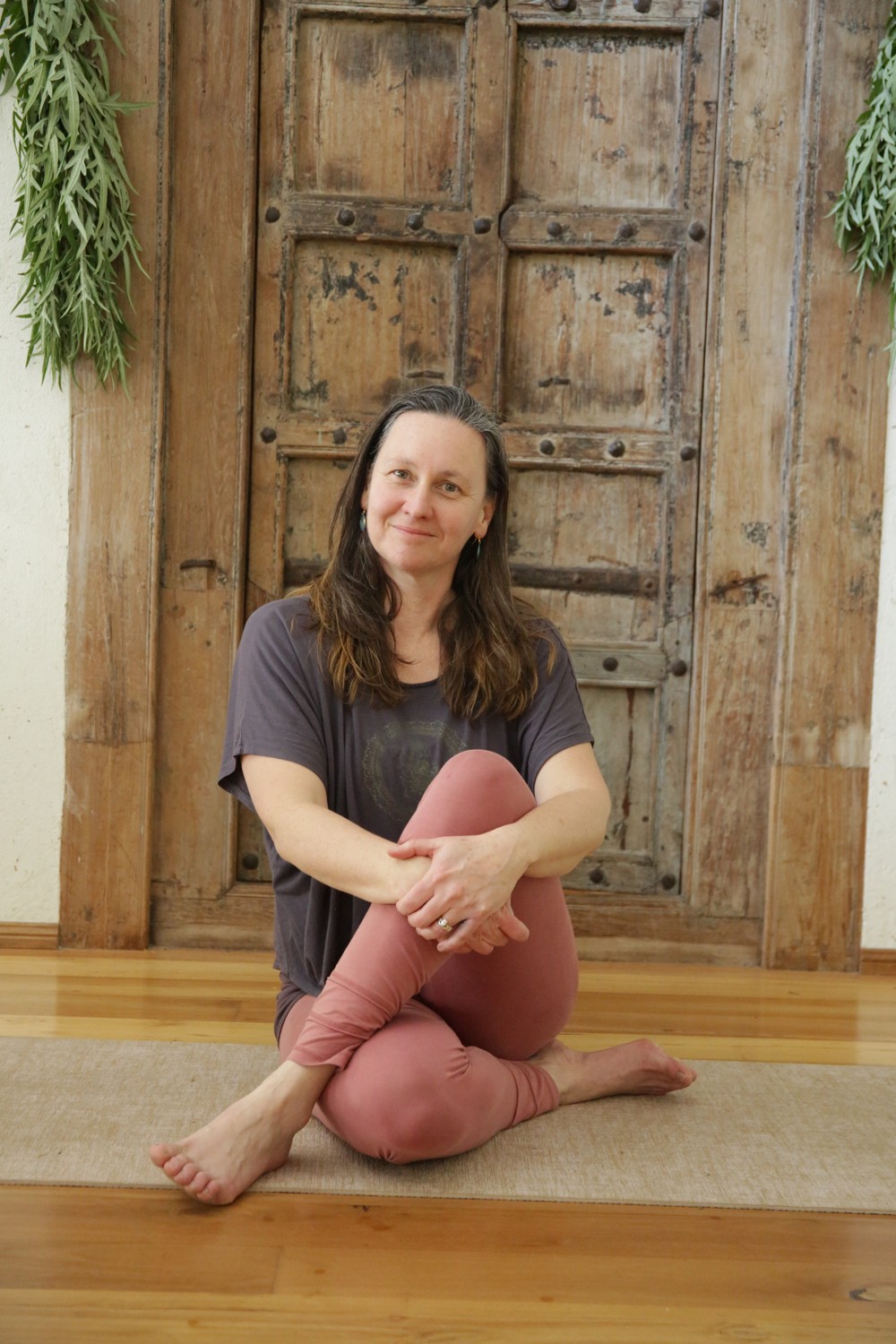 Tamara seated on a yoga mat in a peaceful studio